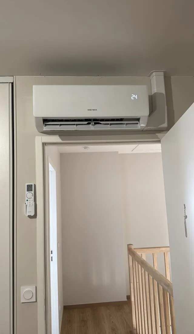 Climatisation HEIWA au-dessus d’une porte, avec télécommande murale