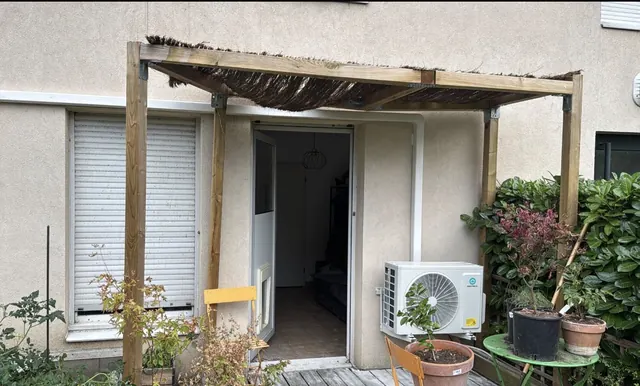 Unité extérieure HEIWA en façade, à proximité d’une pergola