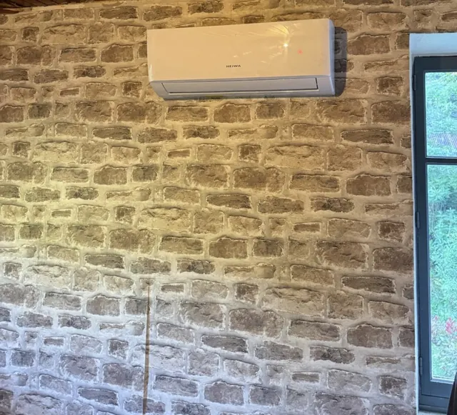 Unité intérieure HEIWA installée sur un mur en pierre