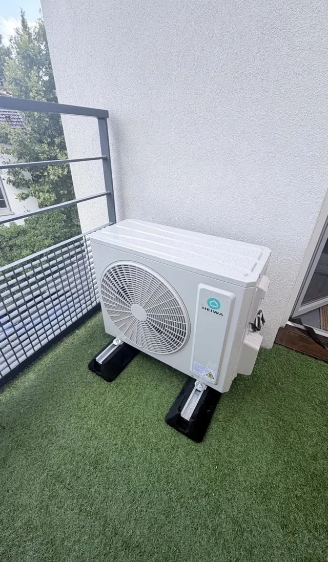 Unité extérieure HEIWA posée sur supports sur un balcon