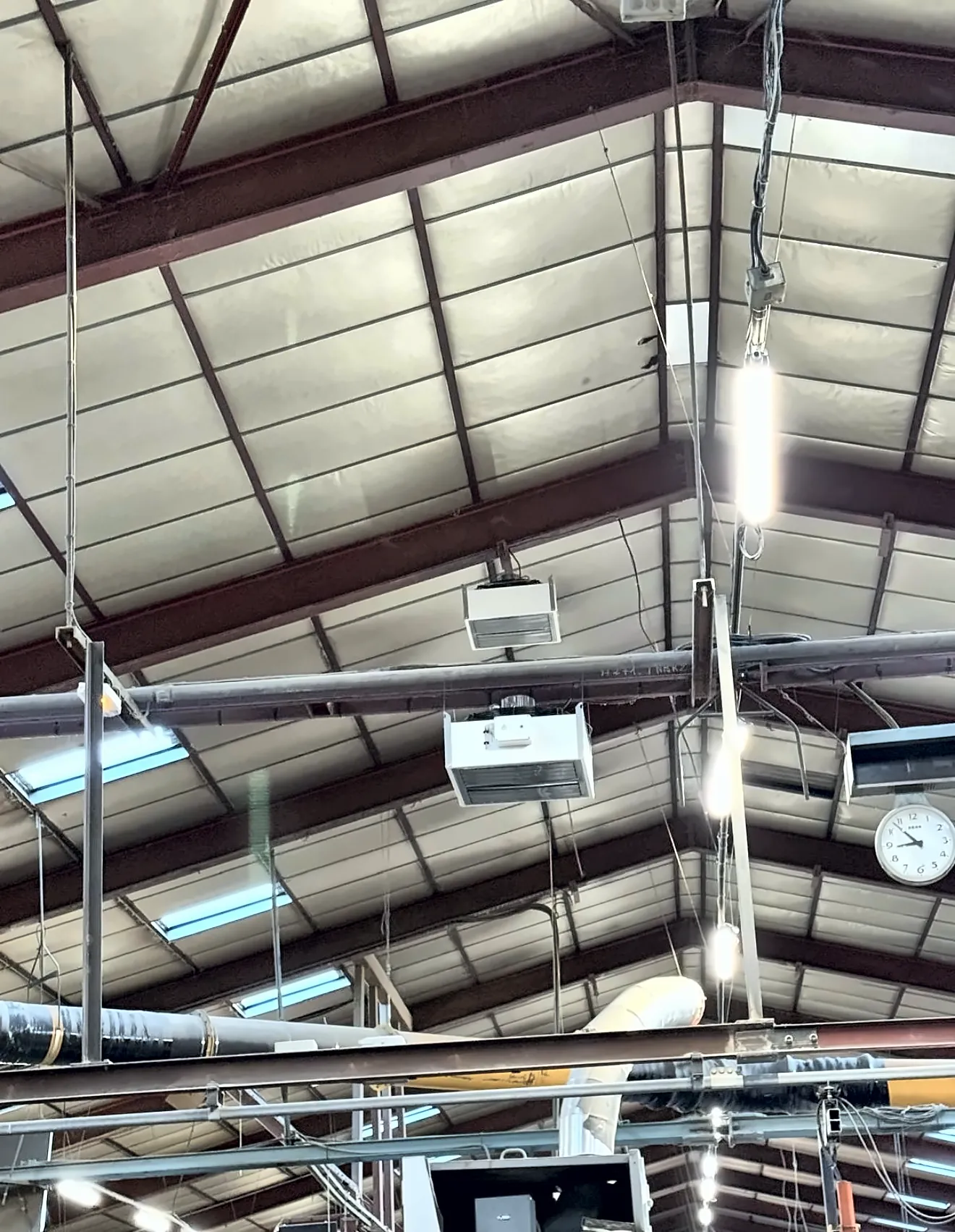 Déstratificateurs suspendus sous la charpente métallique d’un atelier de grande hauteur